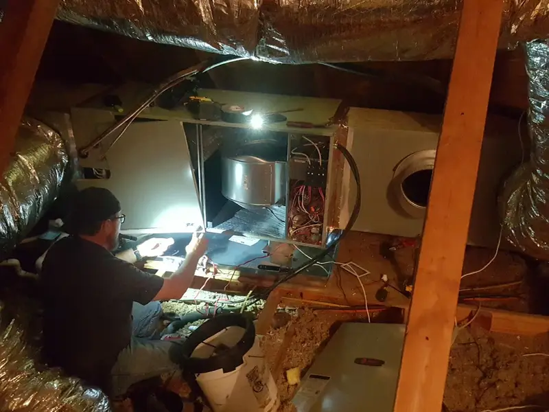 TLC technician working on a furnace in an attic